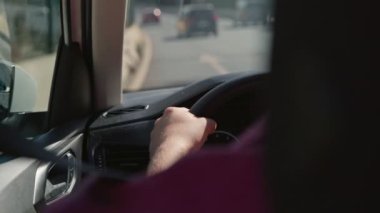 Direksiyonu sıkıca kavrayan bir sürücüyü açık bir yolda yürürken yakına çeken bir fotoğraf.