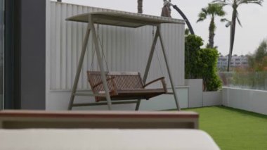 Huzurlu ve huzurlu bir teras ortamında, mükemmel bir rahatlama için mükemmel bir açık hava salıncak koltuğu.