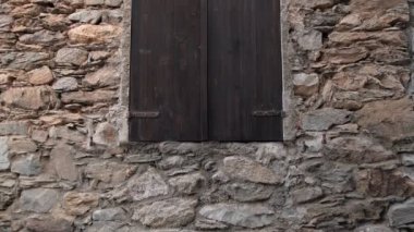Kapalı ahşap kepenkleri olan güzel yıpranmış taş bir duvar, kırsal bir estetik tasarım için idealdir.