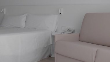 Huzurlu ve huzurlu bir minimalist otel odası rahat bir yatak ve rahatlamak için şık bir şezlonga sahip.