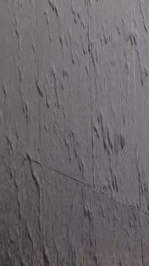 Yağmurlu suyla kaplı ıslak bir duvar fırtınanın şiddetini vurgular..