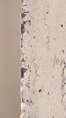 Yumuşak ışık altında sert yüzeyini ve doğal kusurlarını gösteren desenli beton bir duvarın yakın görüntüsü..