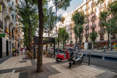 Madrid, İspanya - 13 Temmuz 2019. Madrid, İspanya 'da klasik Avrupa mimarisi, açık hava kafeleri ve park etmiş scooterların yer aldığı manzaralı bir cadde..