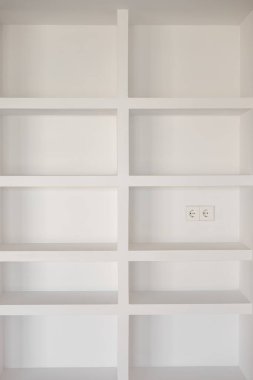 Simetrik depolama bölümleri olan beyaz bir bitiş noktasında duvara monte edilmiş çağdaş bir raf ünitesi.