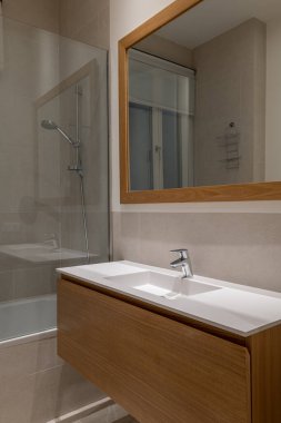 Büyük çerçeveli bir ayna, gösterişli bir ahşap kibir ve rafine bir dokunuş için sıcak tarafsız fayanslar içeren rahat ve zarif bir banyo..