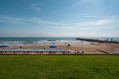 Sitges 'de güneşli yatakları ve şemsiyeleri olan kumlu güzel bir sahil açık gökyüzünün altında rahatlatıcı bir deniz deneyimi sunuyor..