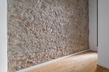 Çağdaş bir iç uzayda, kırsal ve modern elementleri birleştiren dokulu bir taş duvar..