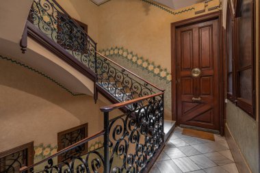 Sanatsal işlemeli demir parmaklıklar ve zengin ahşap kapı tasarımları içeren samimi bir üst düzey iniş.