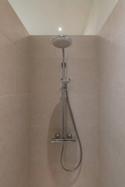 Nötr tonlu basit ama zarif bir banyo, yağış başlığı ve rahatlatıcı bir atmosfer yaratmak için hafif bir ışık..