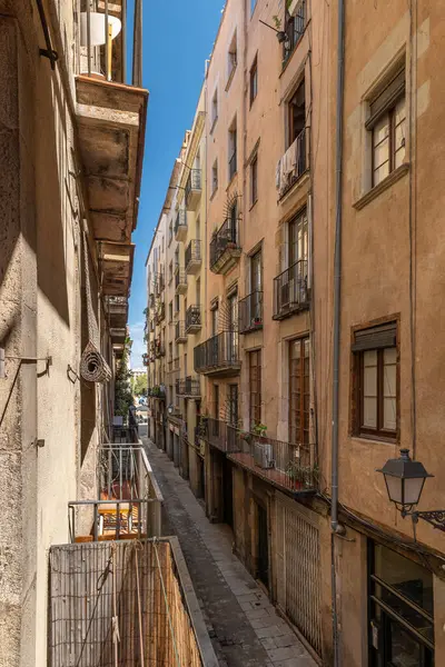 Dar bir Barselona caddesi. Tarihi cepheleri, küçük balkonları ve sıcak güneş ışığı filtreleri..