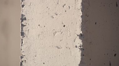 Güneş ışığının altındaki çatlaklardan ve sert dokulardan oluşan yıpranmış beton bir duvarın yakın çekimi..