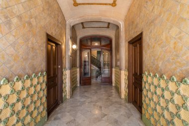 Klasik ahşap kapılar, parlak mermer döşemeler ve süslü fayans desenleri olan şık bir koridor.
