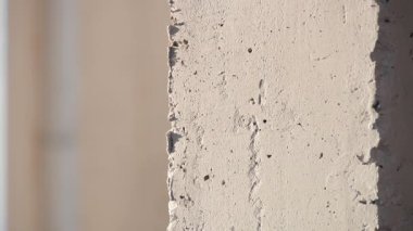 Beton bir duvarın açıkta kalmış bir köşesinde görünür çatlaklar ve doğal ışık kusurları var..