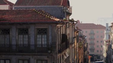 Kırmızı çatıları ve renkli fayansları olan binalar parlak pembe bir apartman bloğuna uzanan dik bir cadde.