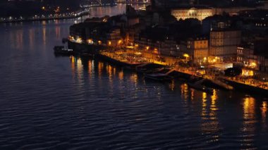 Parlak sokak lambaları ve nehir üzerindeki yansımalar Porto 'nun eski kentinin mimari güzelliğini artırıyor.