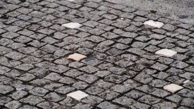 Koyu bloklar arasında dağınık açık renkli kiremitlerle ızgara desenli taş kaldırımın ayrıntılı görüntüsü