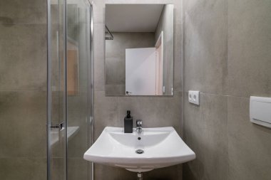 Gri desenli duvarları olan modern banyo temiz beyaz lavabo ve cam duş alanı.