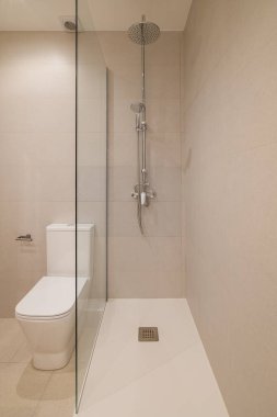 Geniş bej duvar kiremitleri ve krom yağmurlu duşa uygun modern duş alanının yakın görüntüsü