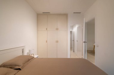 Temiz minimalist bir yatak odası. İç döşeme, gömme gardırop ve iki kapı.
