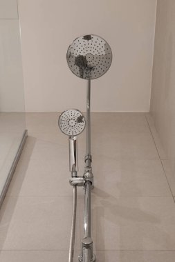 Yağmur stili krom duş başlığı ve el yapımı duş başlığını gösteren bir banyo fotoğrafı.