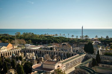 Barcelona 'daki eski bir mezarlığın manzarası yükseldi. Sakin sahil kenarındaki süslemeli mezarlıklar ve anıtsallar palmiye ağaçları ve park alanlarıyla doluydu.