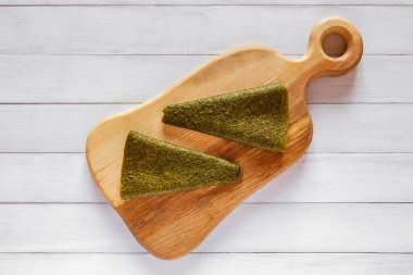 İki üçgen yeşil meyveli pastil. Açık tahta üzerine dizilmiş. Doğal bir kırsal görünüm yaratıyor.