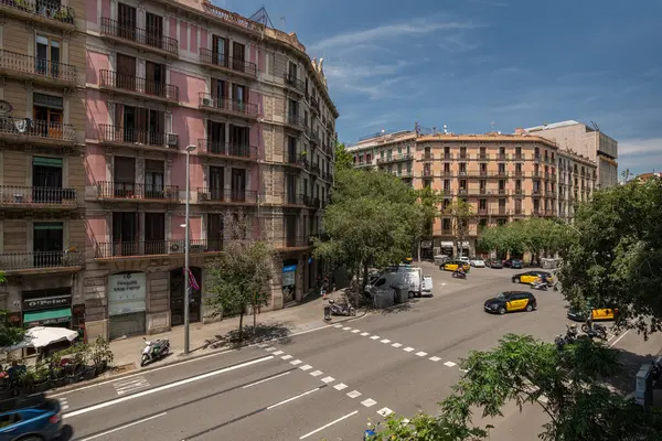 Barselona, İspanya - 13 Temmuz 2024. Barcelona Eixample kesişme sahnesi renkli cephelerle ve taksiler ve scooterlar dahil aktif trafikle