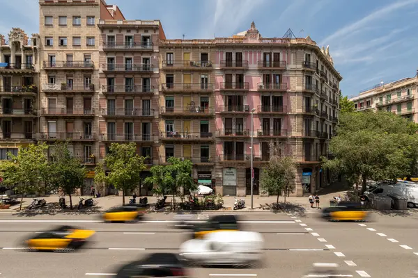 Barselona, İspanya - 13 Temmuz 2024. Süslü balkonlarla simetrik cephe ve Eixample mahallesinde geniş bir caddede trafiği hareket ettirme