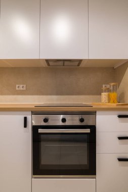 Mutfak ön çekimi, fırın, mutfak, beyaz dolaplar ve ahşap tezgahları gösteriyor.