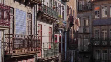 Yoğun bir yerleşim bölgesinde çeşitli kiremit desenleri ve dövülmüş demir balkonları olan güneşli Portekiz daireleri.