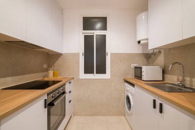 Temiz ve düzenli mutfak, beyaz dolaplar, ahşap tezgah, buzdolabı, mikrodalga ve lavabo.