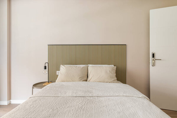 В интерьере спальни есть двуспальная кровать с белыми подушками бежевого цвета, ребристая спинка спинки спинки спинки спинки спинки спинки спинки спинки спинки спинки кровати.