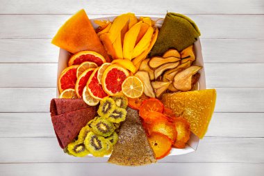 Karışık kurutulmuş meyve ve rulo meyve derileri bir kutuda düzenlenmiş canlı renkli bir hediye seti yaratıyor.