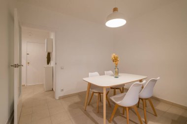 Beyaz masalı modern yemek odası ve temiz ve basit bir odada kolye lambası altında sandalyeler.
