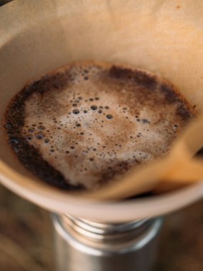 Doğal ortamda demlenen kamp sırasında yerden kabarcıklar yükselirken filtrede taze kahve açar.