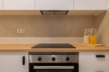 Simetrik mutfak manzarası fırın, fırın, kabin ve makarna ve yulaf dolu iki kavanoz gösteriyor.