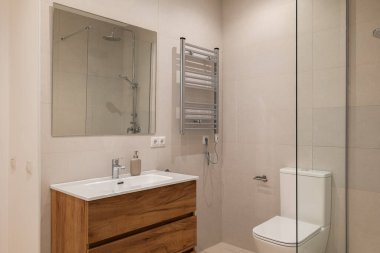 Modern banyo içinde ahşap kibir, krom havlu ısıtıcı ve cam duş muhafazası var.
