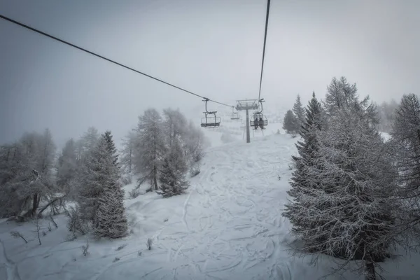 리프트는 안개낀 눈덮인 산에서 스키를 타거나 스노보드를 사람들을 케이블카에요 마돈나 — 스톡 사진