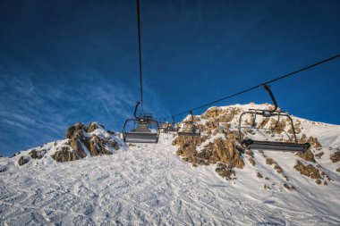 Güneşli kış gününde Nassfeld kayak merkezinde ve dağlarda sandalyelik kaldırma. Carinthia, Avusturya. Ocak 2022