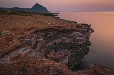 İtalya, Sicilya, Trapani bölgesi, San Vito Lo Capo, Akdeniz, Tyrhenian denizi, Macari Körfezi akşam saatlerinde kırmızı ışıkta parladı. Haziran 2023