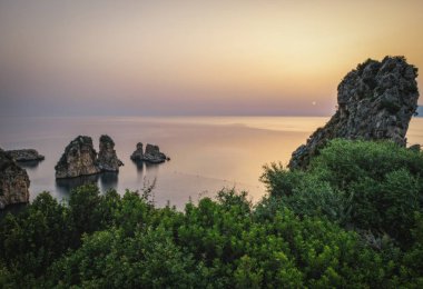 İtalya 'nın Sicilya kenti Castellammare del Golfo yakınlarındaki Scopello sahilinde kayalıklar. Haziran 2023, uzun pozlama fotoğrafı, gün doğumu zamanı.