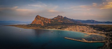 San Vito Lo Capo 'nun panoramik fotoğrafı Sicilya' da küçük bir sahil beldesi. Monte Monaco 'nun hakim olduğu sahile bakan sahili ile ünlüdür. Kristal berrak deniz. Hava aracı atışı, Haziran 2023