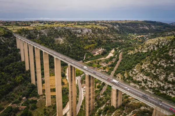 Haziran 2023. İtalya 'nın Ragusa Sicilya kentindeki Modica Bassa ve 115 Güney Sicilya eyalet yolu üzerindeki Ponte Guerrieri karayolunun panoramik manzarasına sahip hava manzarası..