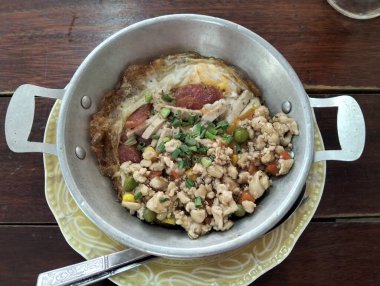 Geleneksel Tayland-Vietnam Pan Yumurtalı Kahvaltısı. Küçük alüminyum tavada servis edilen otantik tarzda kahvaltı. Üst görüntüde tavada kızarmış yumurta, kıymalı kıyma ve dilimlenmiş sosis var.