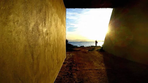 The silhouette of a person, a sunset over the sea and a streaked sky can be seen from the entrance to a railway underpass.