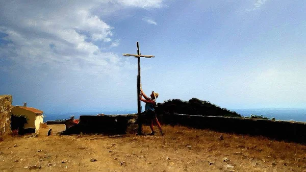 A woman prays at the foot of a wooden cross on the hill.