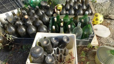 Ozieri, Sardunya, İtalya. 21 Ağustos 2021. Kırsalda kullanılmış ve terk edilmiş şarap şişeleriyle dolu plastik kutular..