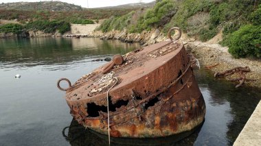Paslı metal silindirik konteynır taş plajın kıyısına bırakılmış..