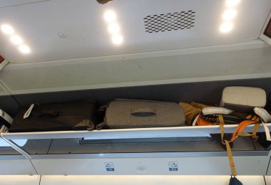 Bir tren vagonunda koltukların üstündeki bölmelere yerleştirilmiş..