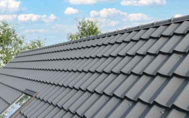 Çelik çatı kaplaması olan kapalı bir çatı. Geleneksel metal kiremitler. Gri modüler fayans efekti çatı paneli. Çamur ya da beton levha olarak metalik kıvrımlı külotlar. Bina kapatıyor.